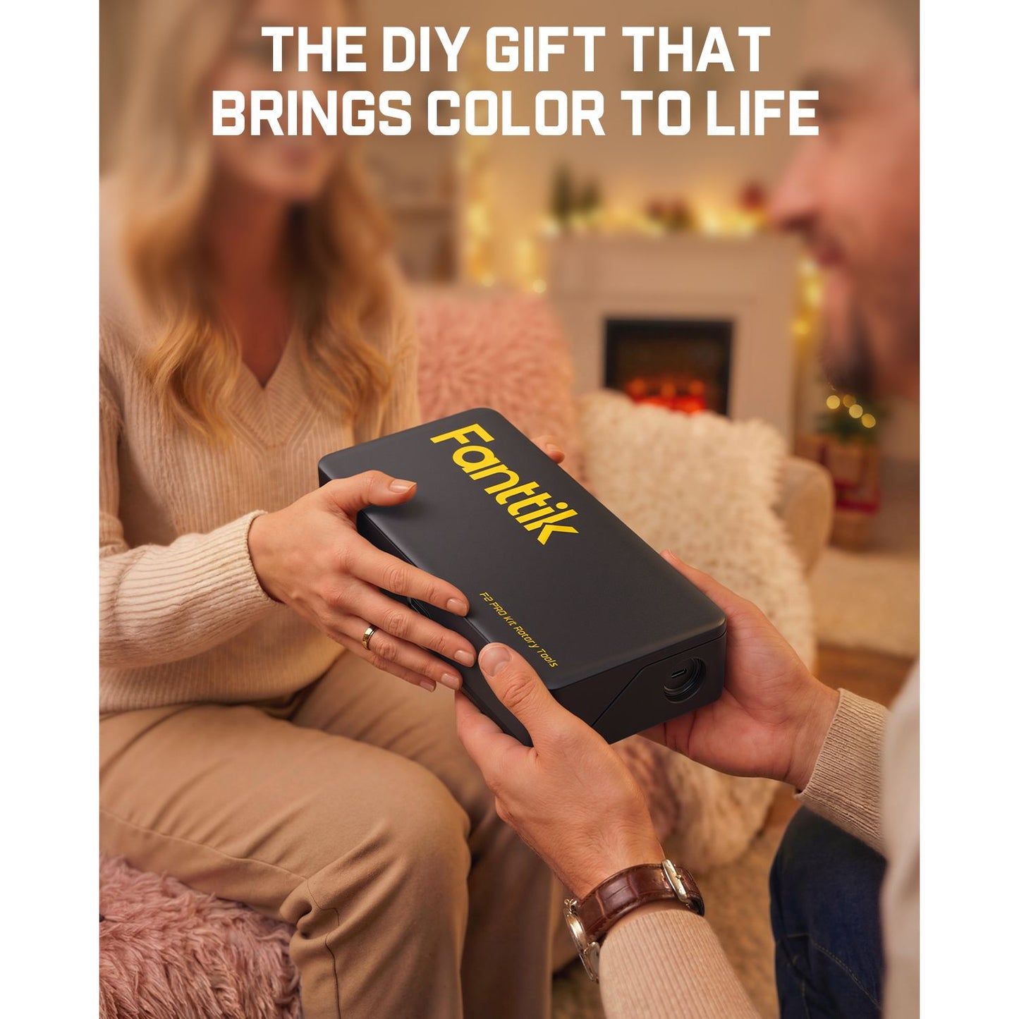 Person holding a black box with 'Fanttik' branding, sitting on a couch in a cozy living room.