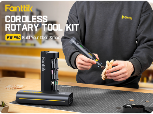 Person using a Fanttik cordless rotary tool kit with tools and accessories on a table.